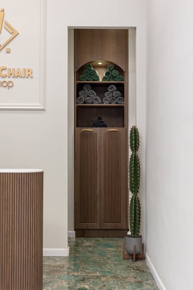 Η εσοχή με τις πετσέτες στο Barber's Chair: ξύλινο ντουλάπι με ρολά από πράσινες και γκρι πετσέτες